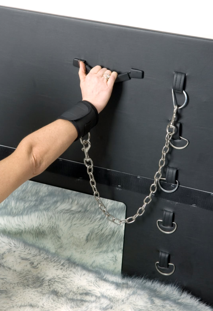 Close-up of black board with wrist cuff, chain and steel rings